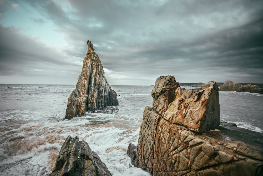 brown rock formation on white snow covered ground under gray cloudy sky during daytime