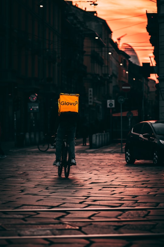 person in black jacket holding umbrella walking on sidewalk during daytime in Milano Italy