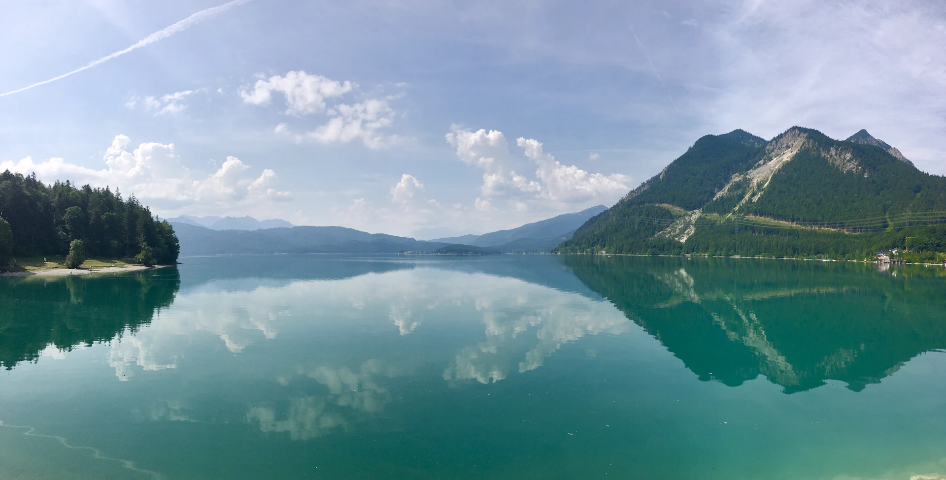 A panoramic shot of a serene lakeside view from a recent tour, with reflections of the surrounding forest.