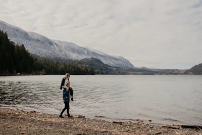 woman in black jacket standing on brown sand near body of water during daytime