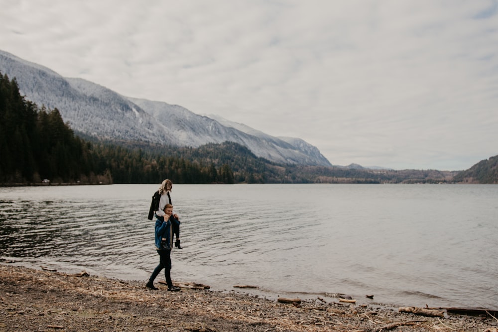 woman in black jacket standing on brown sand near body of water during daytime