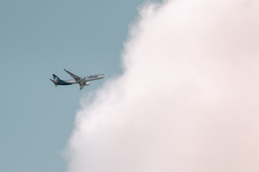 white and blue airplane flying in the sky