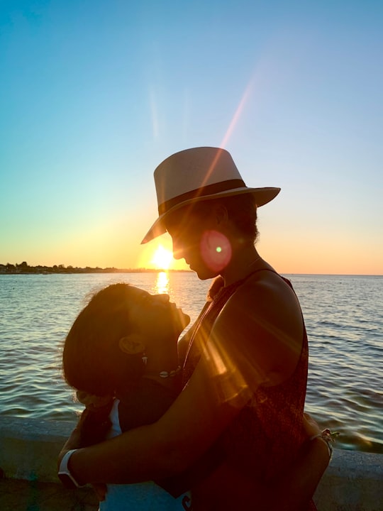 silhouette of woman wearing hat near body of water during sunset in Progreso Mexico