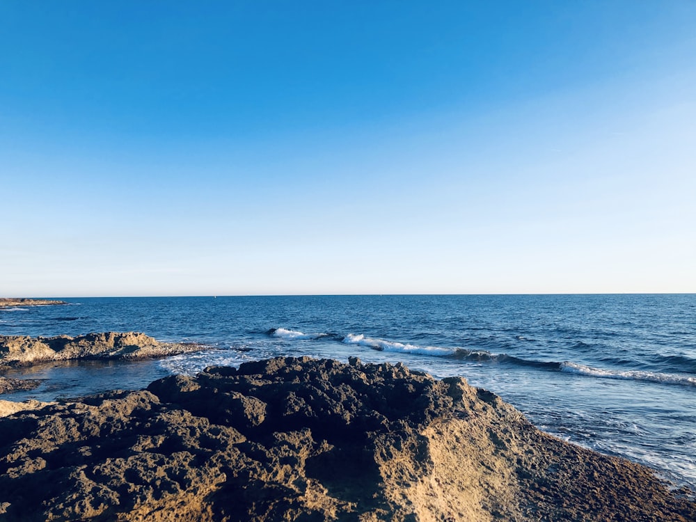 brown rocky shore under blue sky during daytime