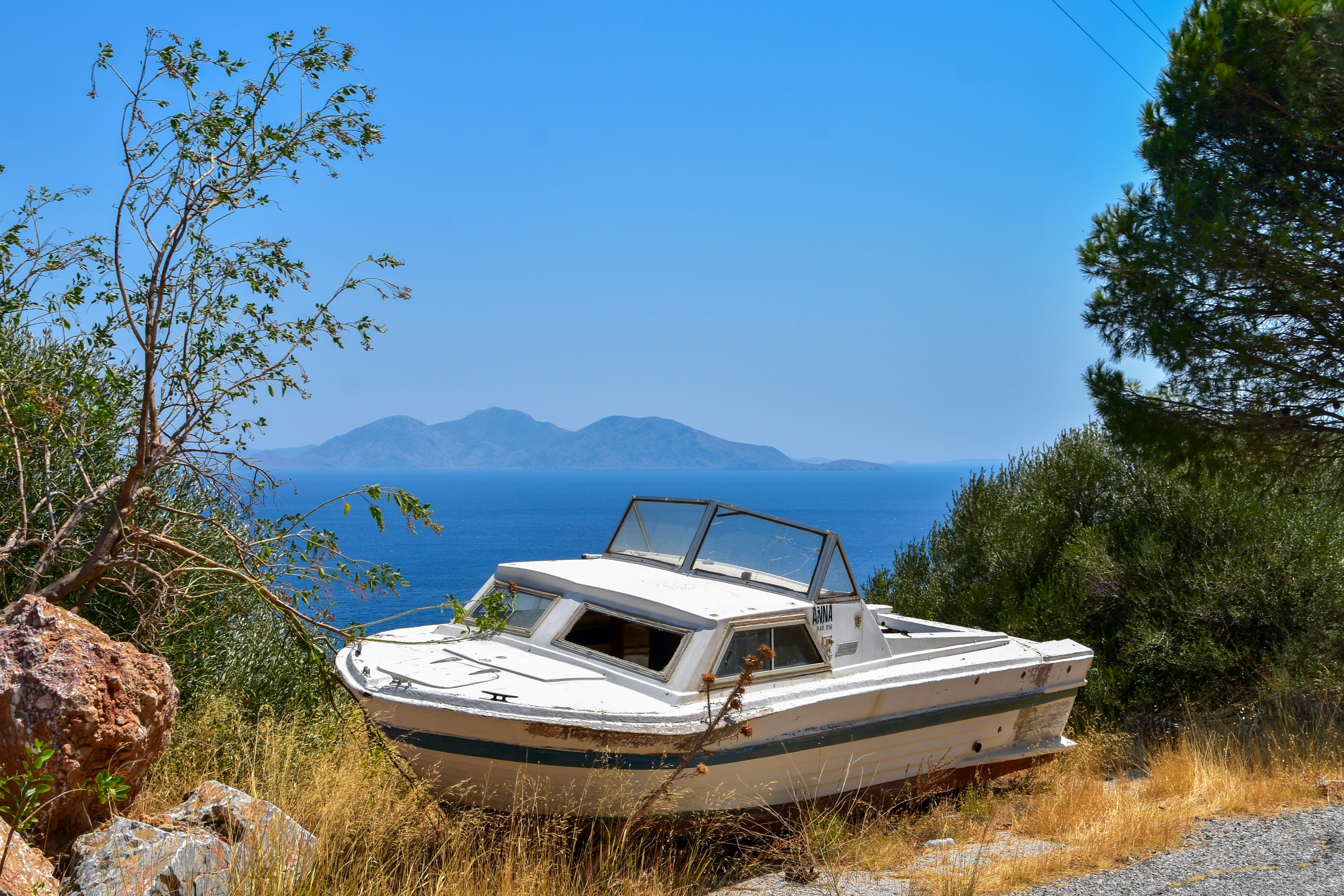 Abandoned boat on a mountain with view of the sea and islands in the distance.