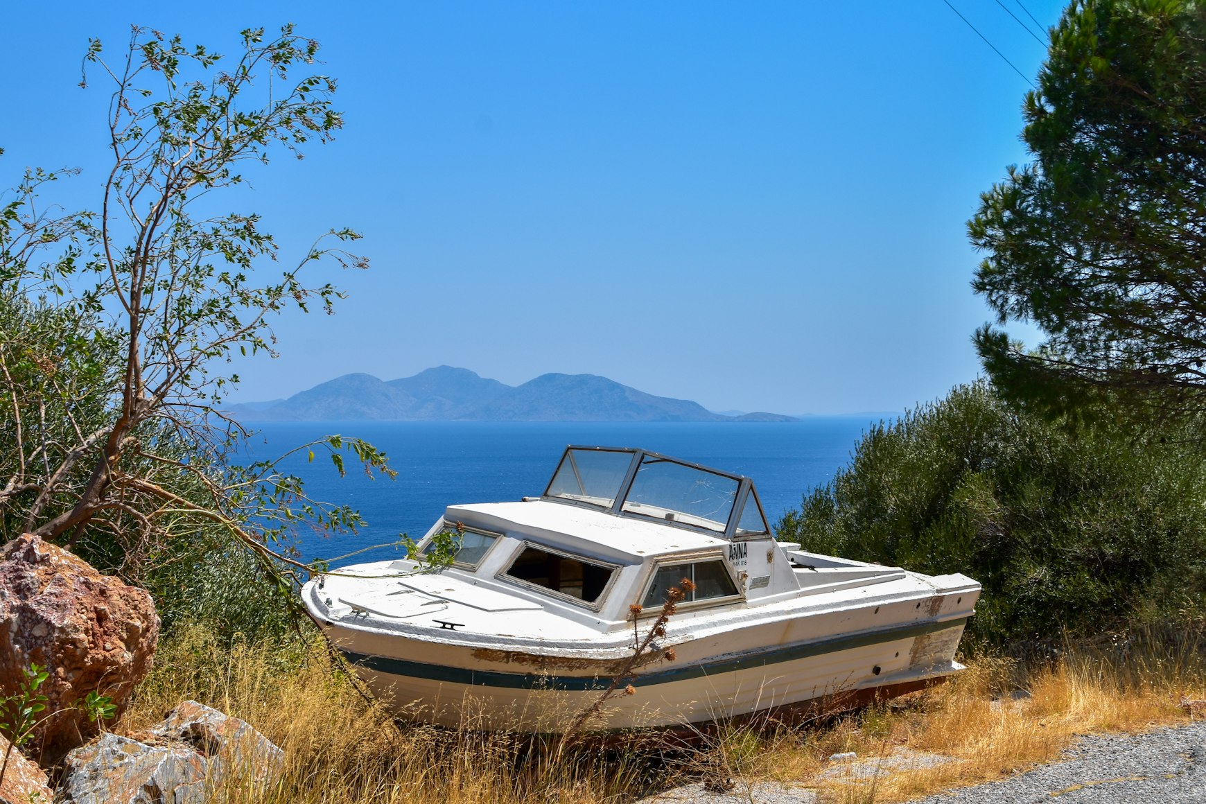 Abandoned boat on a mountain with view of the sea and islands in the distance.