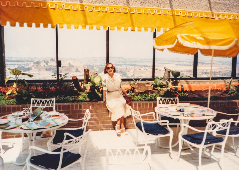 femme en robe blanche debout près de la table et des chaises