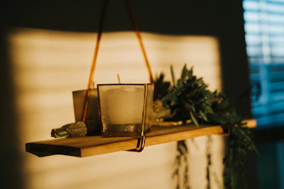A softly lit corner displaying natural candles and delicate butterfly shadow boxes on a wooden shelf.