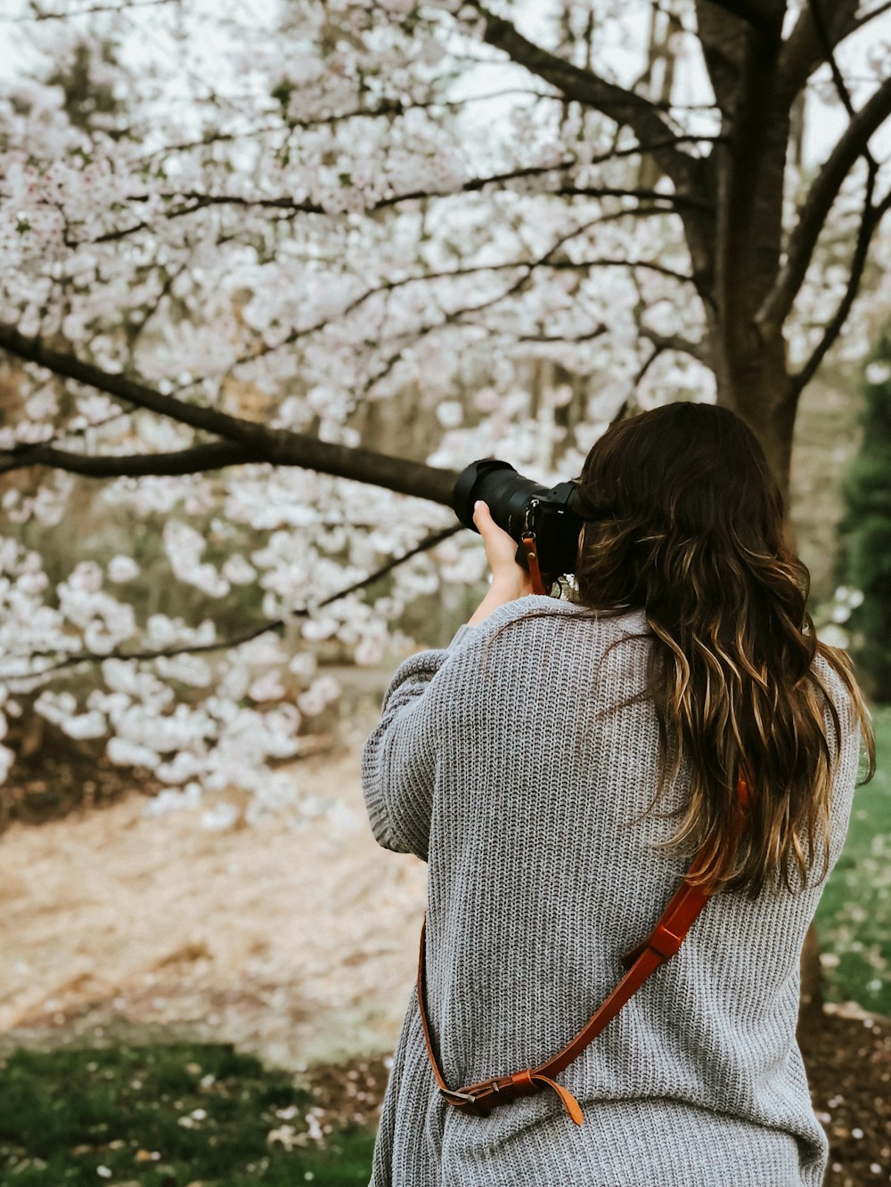 woman in gray and white long sleeve shirt holding black camera