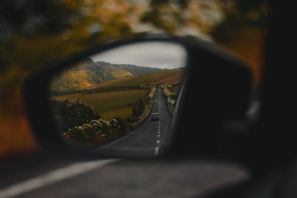 car side mirror reflecting green trees during daytime