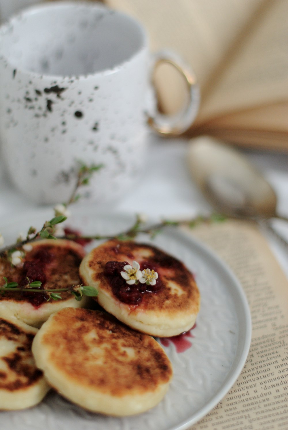 a white plate topped with pancakes next to a cup of coffee