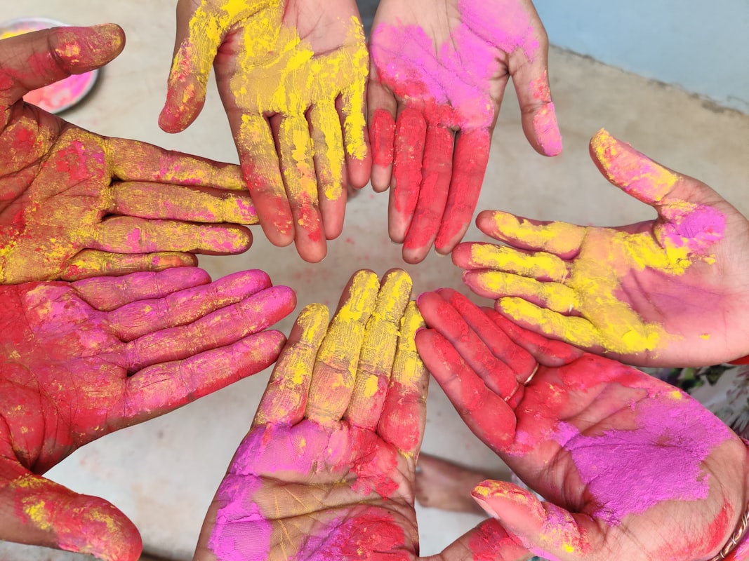 Hands covered in yellow and red Holi powder. Photo by Subhashisa Maharana on Unsplash.