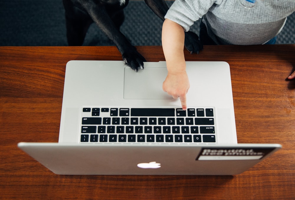 Person, die das MacBook Pro auf einem braunen Holztisch benutzt