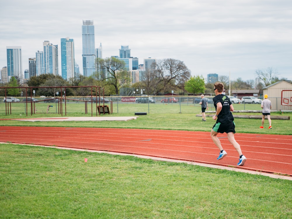 man in black shirt and black shorts running on track field during daytime