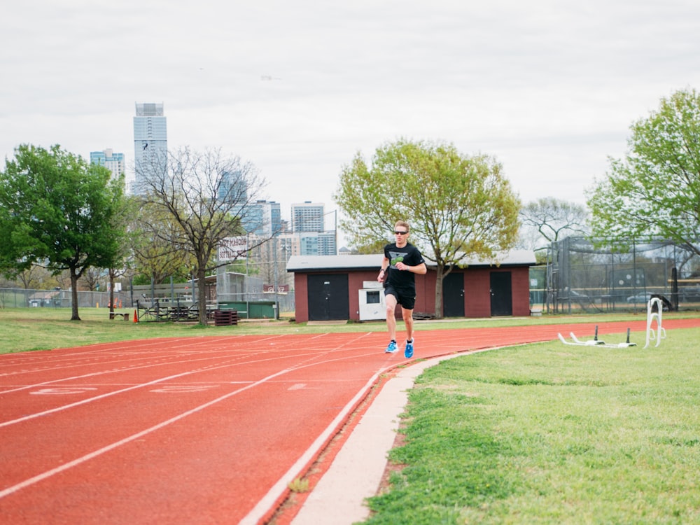 man in black shirt and black shorts running on track field during daytime