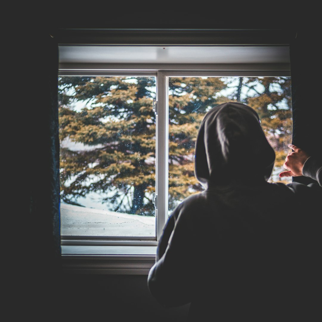 person in gray hoodie looking at the window