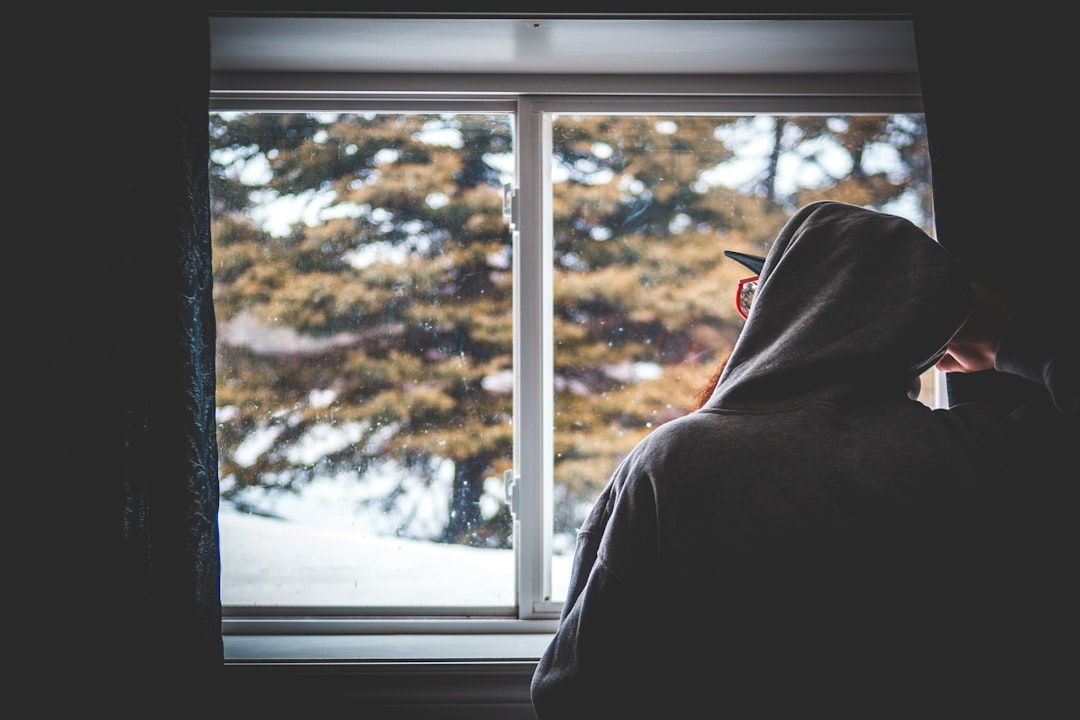 person in black hoodie standing near window