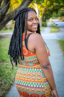 A smiling customer wearing a flowing eco-friendly dress in a green outdoor setting.