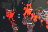 A world map highlighting various regions with large red circles, likely representing data points or incidents across different continents. The dark background makes the red circles stand out prominently, with labels for continents and oceans visible.