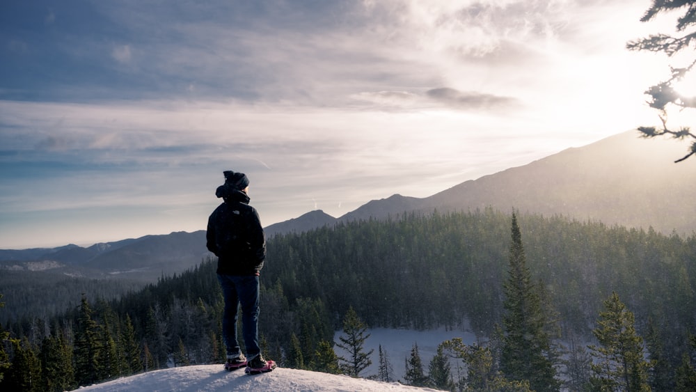 man in black jacket standing on gray rock mountain during daytime