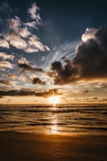 body of water under cloudy sky during sunset