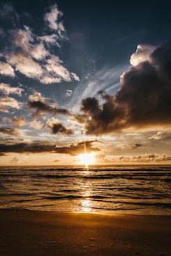 body of water under cloudy sky during sunset