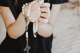 person in black shirt holding white pearl necklace