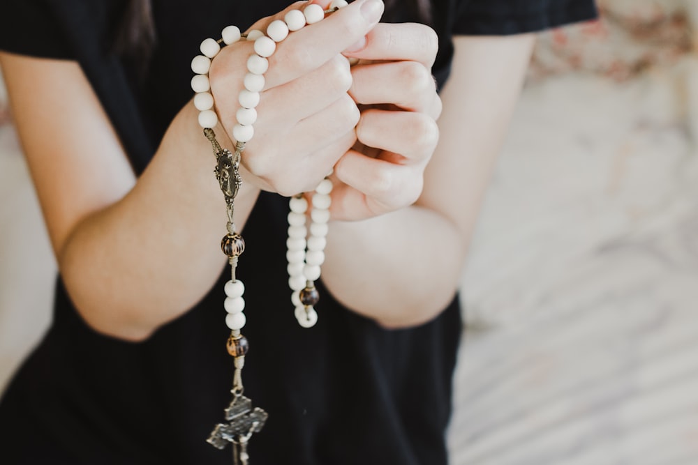 person in black shirt holding white pearl necklace