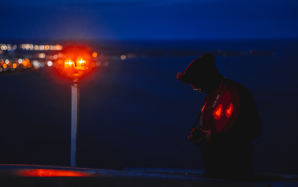 man in black jacket standing on the bridge during night time