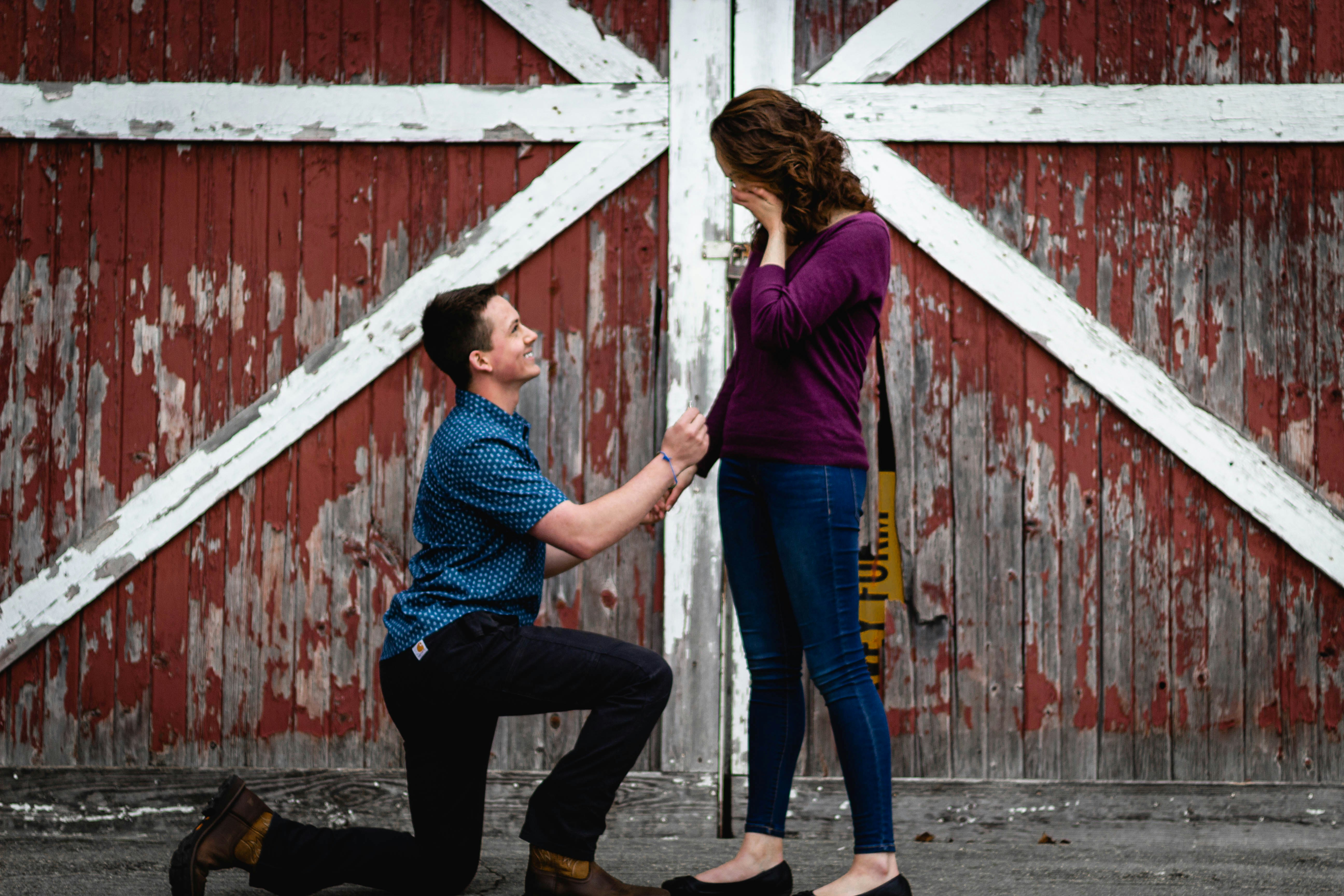 woman in blue denim jeans and red long sleeve shirt standing beside white wooden fence during
