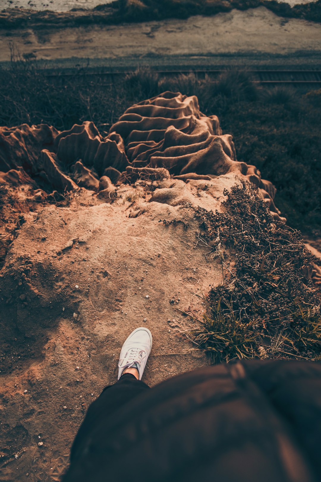 person in white sneakers standing on brown soil