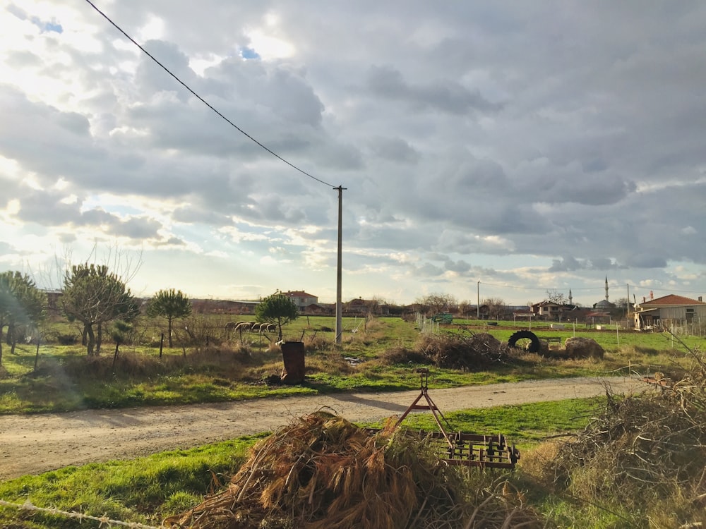 green and black tractor on green grass field under white clouds during daytime