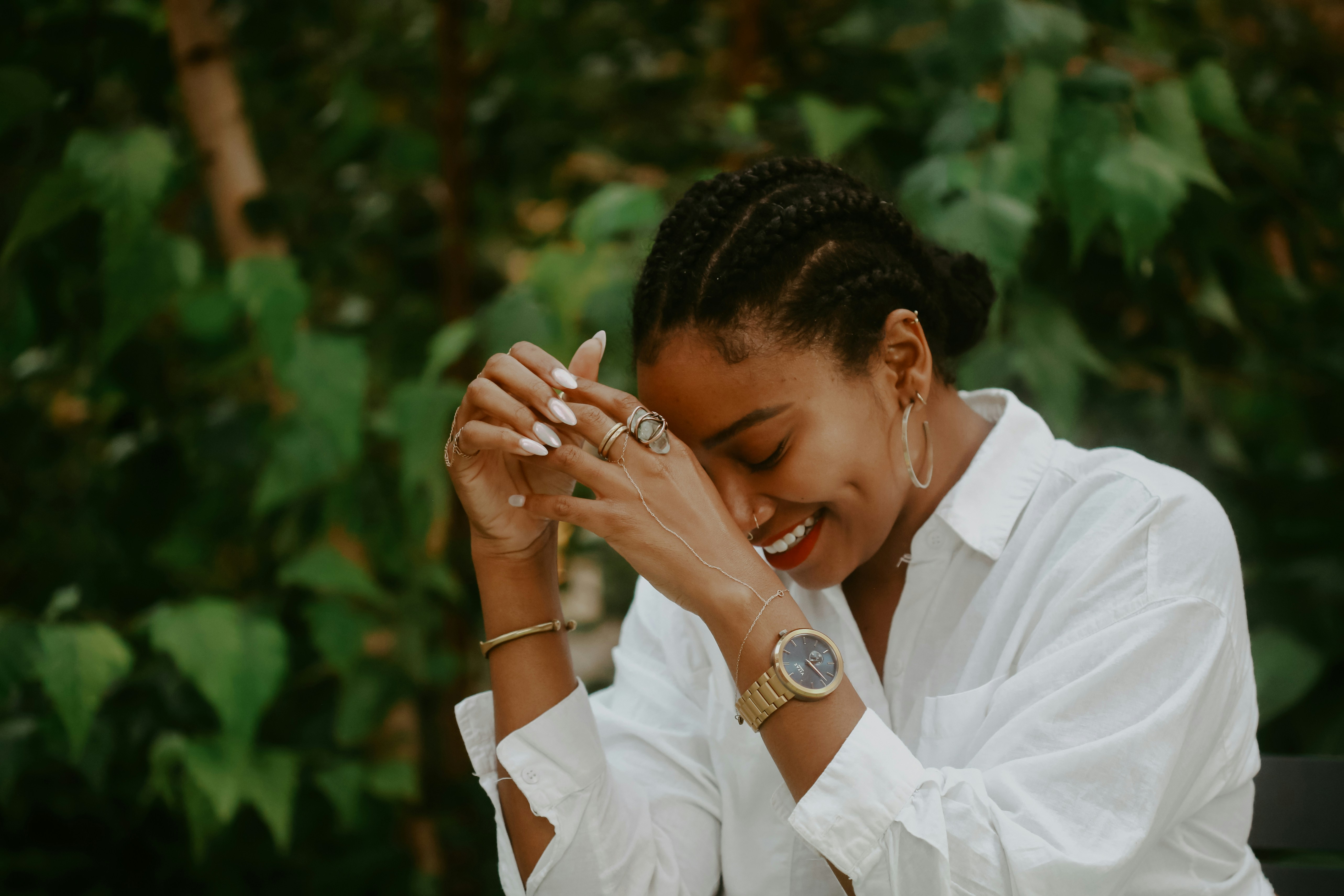 A young black lady, wearing a white shirt with smile on a face. She is reflecting on a funny moment