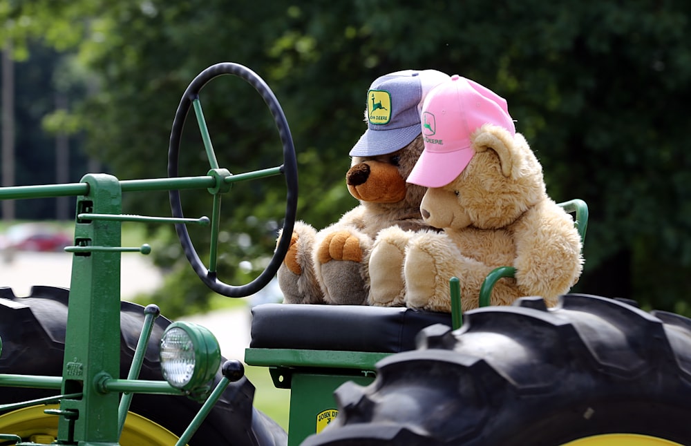 brown teddy bear on green and black tractor