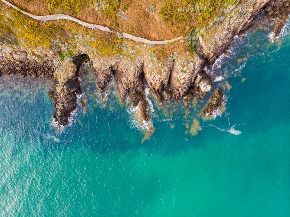 aerial view of green and brown rocky mountain beside blue body of water during daytime