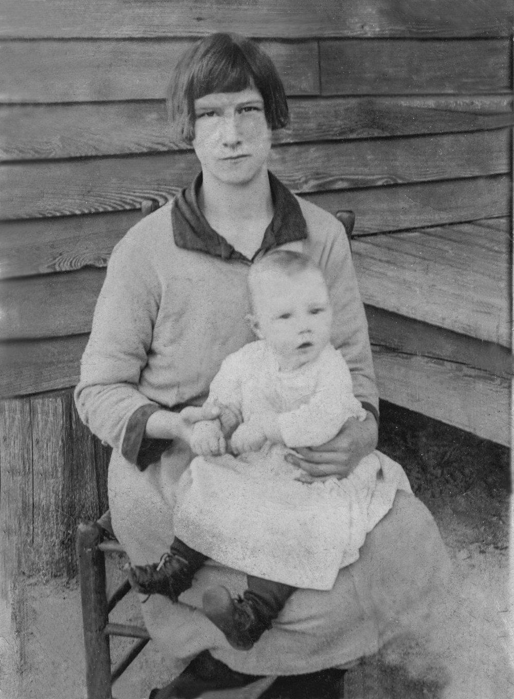 woman in sweater carrying baby in grayscale photography