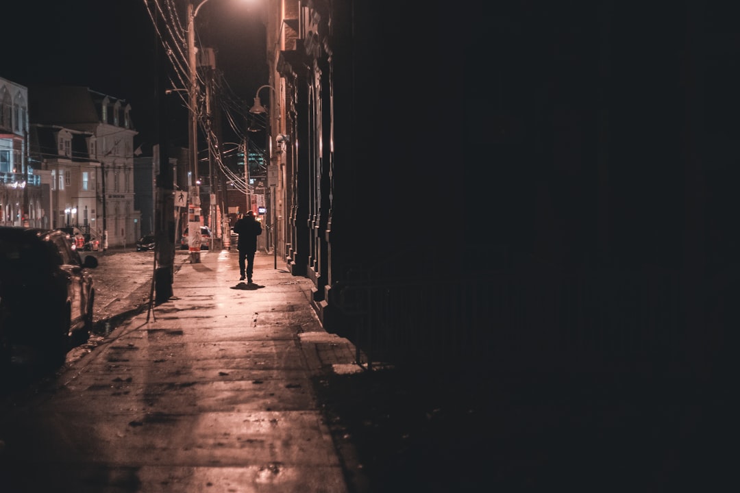 man walking on sidewalk during night time