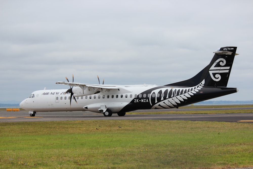 avion blanc et noir sur un champ d’herbe verte sous des nuages blancs pendant la journée