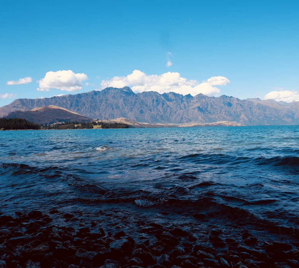 body of water near mountain under blue sky during daytime