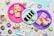 An assortment of colorful, decorated desserts is displayed on vibrant paper plates. There are slices of cake, cupcakes with frosting and sprinkles, and miniature donuts. The scene is set against a backdrop of pastel napkins and festive confetti scattered around the surface.