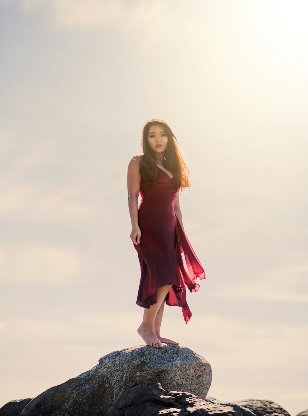 woman in purple sleeveless dress sitting on rock