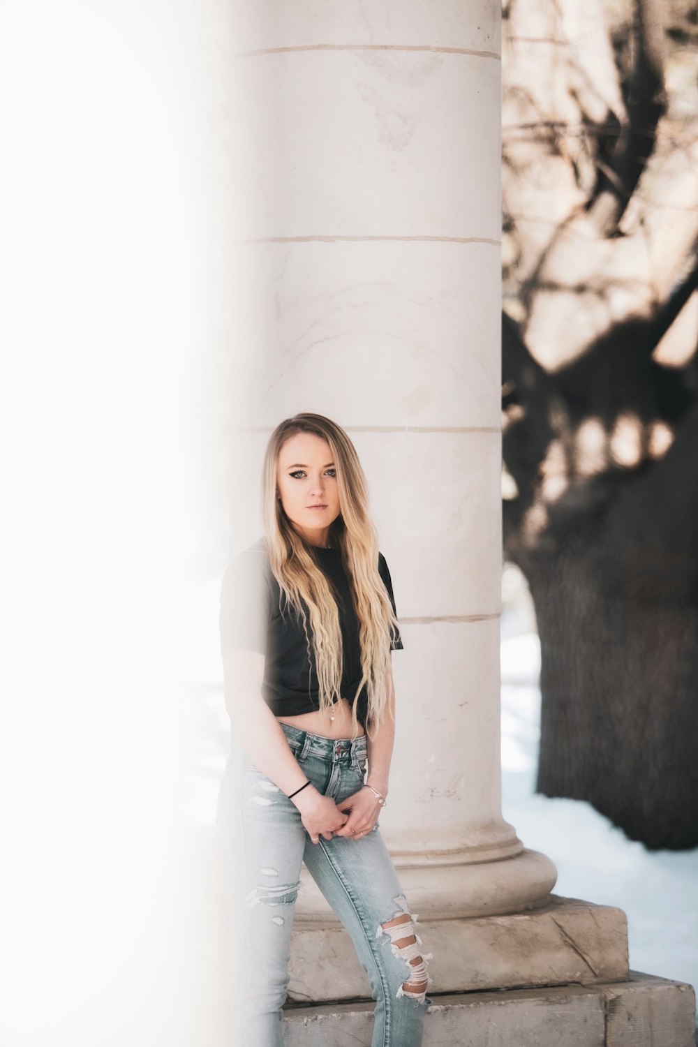 woman in white t-shirt and blue denim shorts standing beside white concrete wall during daytime