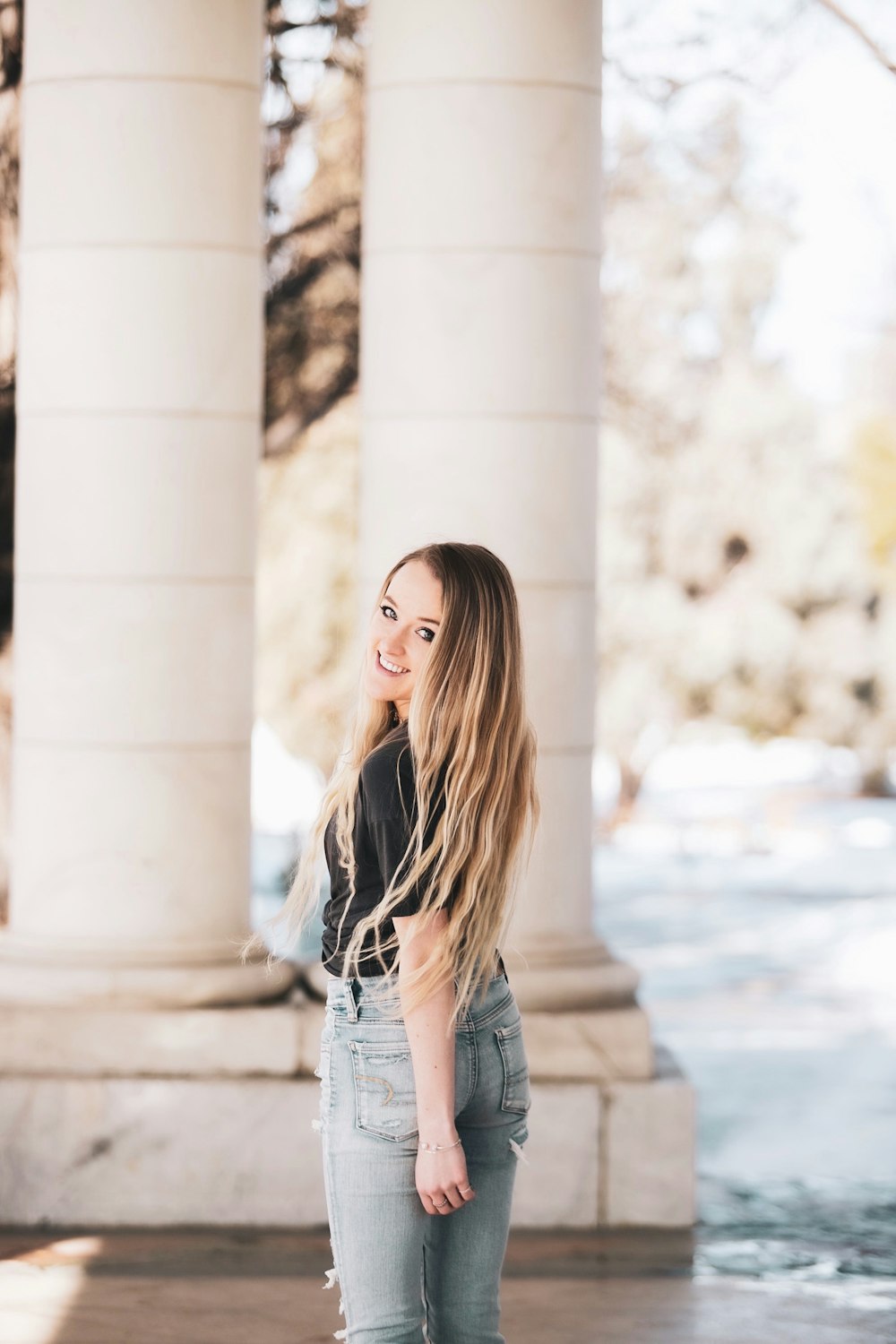 woman in blue denim jacket standing near white concrete pillar during daytime