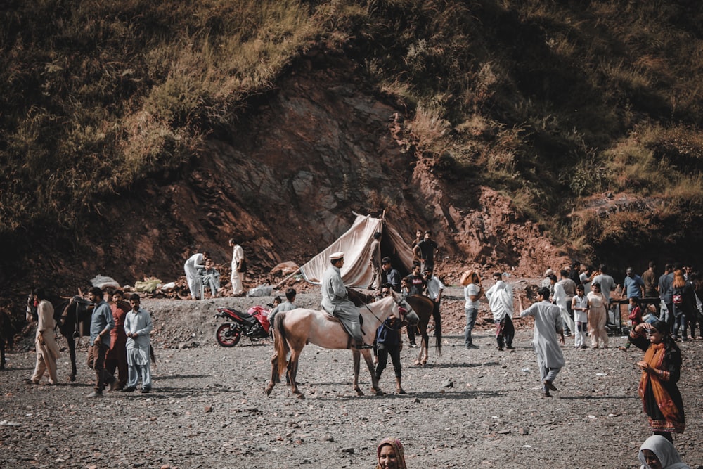 pessoas andando a cavalo perto da montanha marrom durante o dia