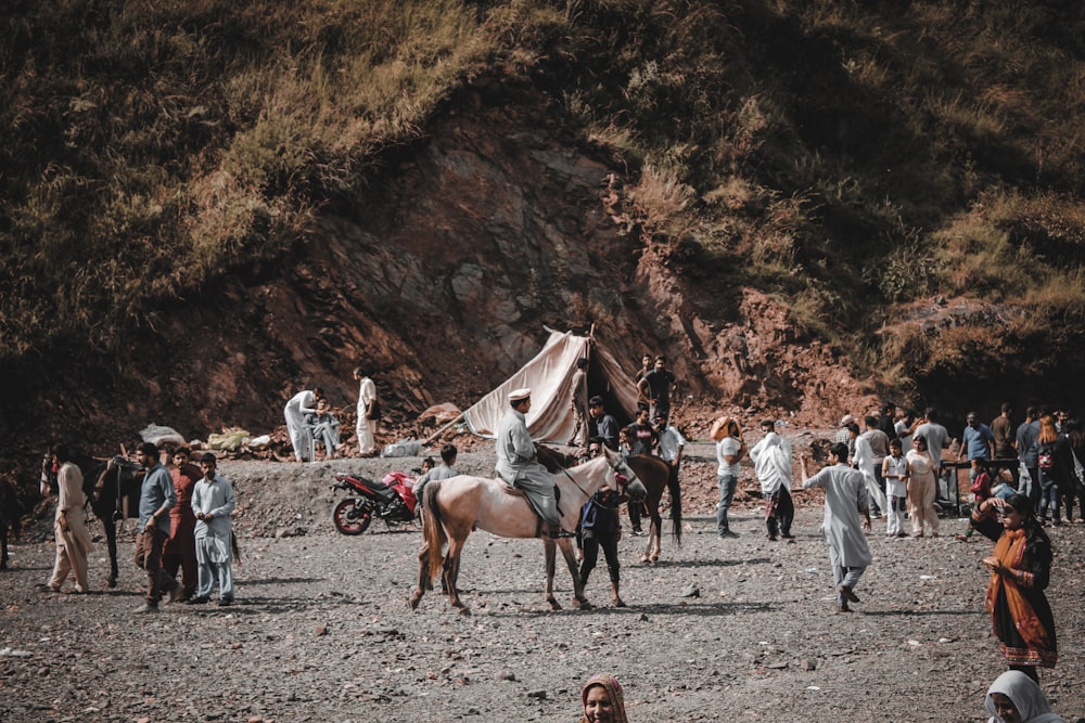 people riding horses near brown mountain during daytime