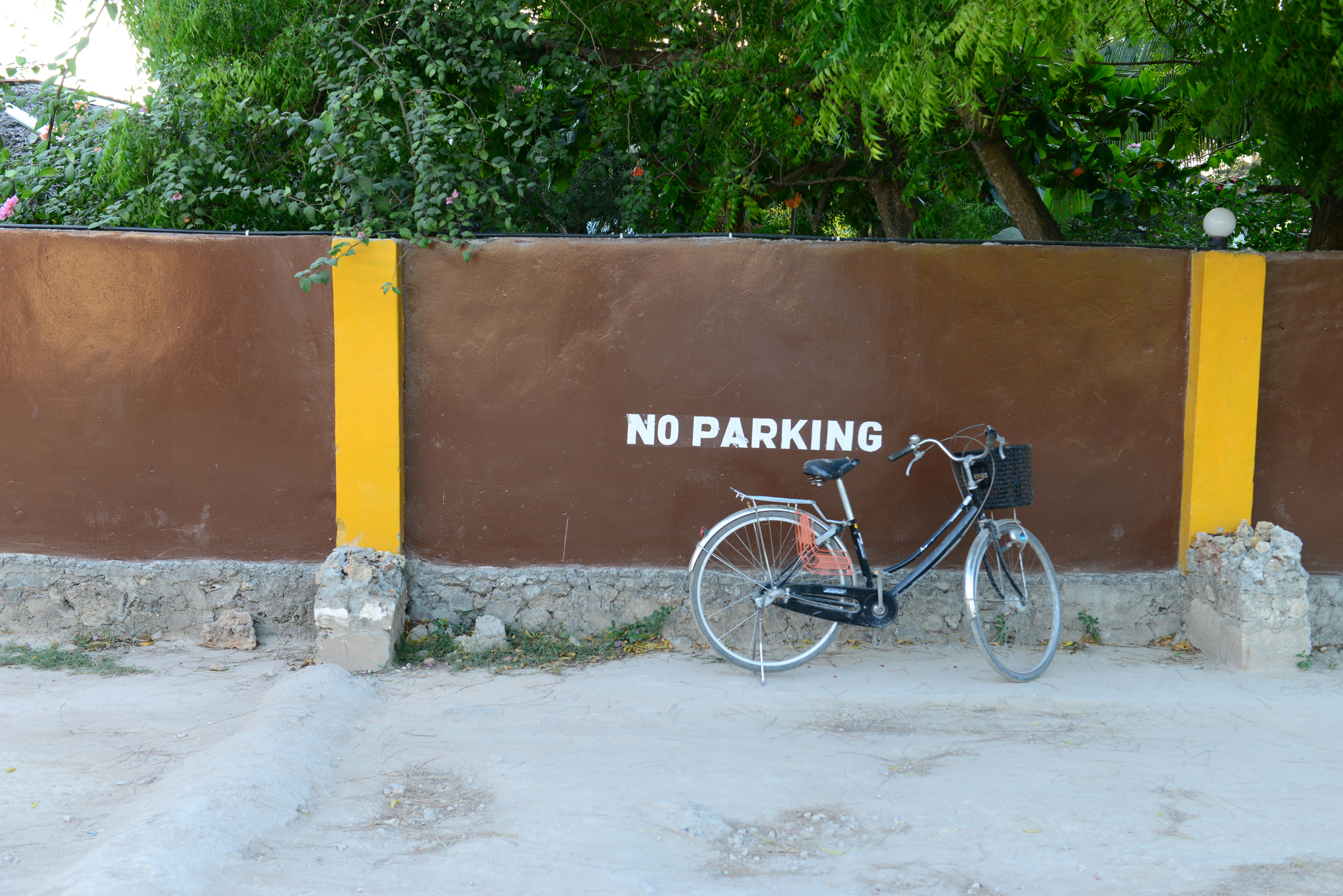 black city bike parked beside yellow concrete wall
