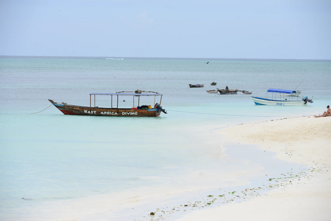 A wooden boat resting on the powder-white sand of a deserted beach in Zanzibar, Tanzania