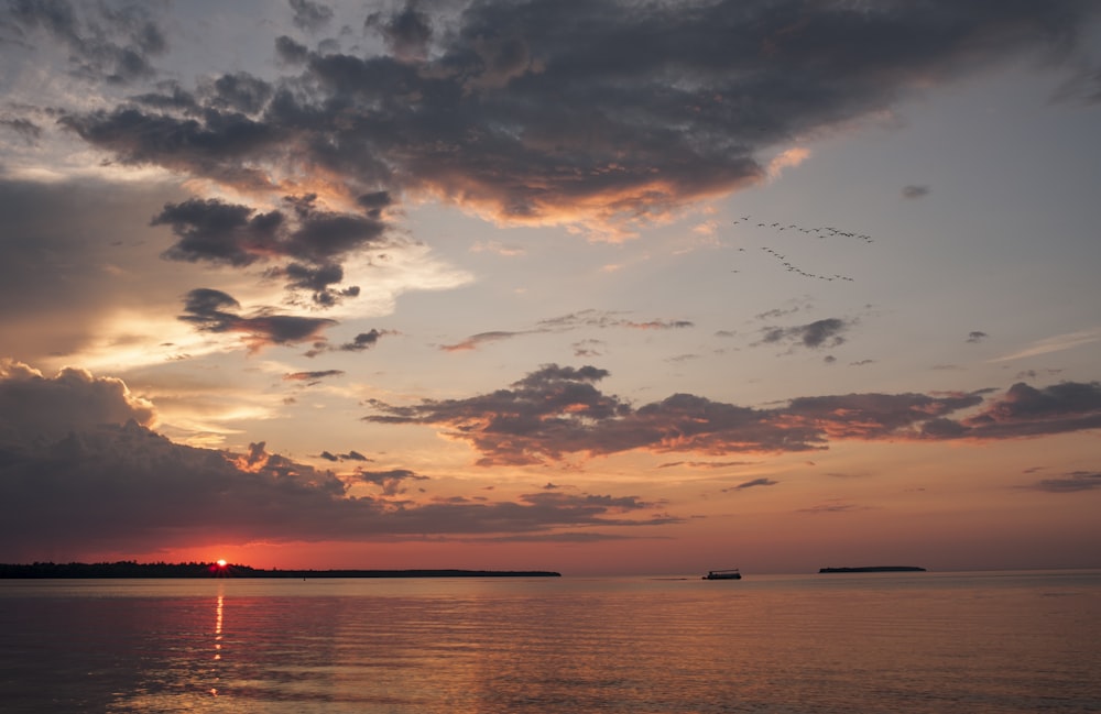 body of water under cloudy sky during sunset