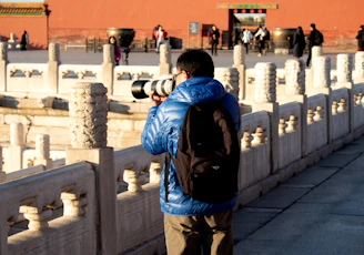 man in blue jacket and brown pants carrying black backpack