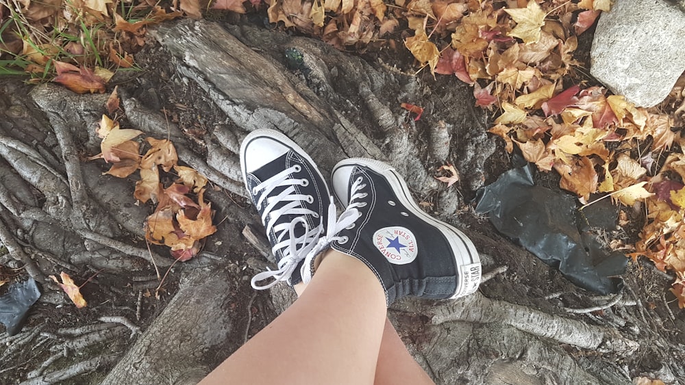 person wearing black and white converse all star high top sneakers
